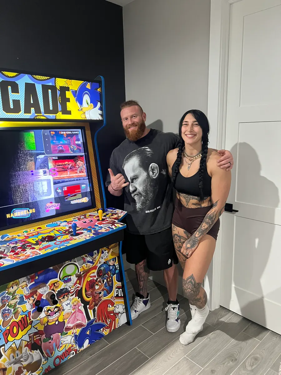 Rhea Ripley & Buddy Matthews with the finished Sticker Bomb arcade